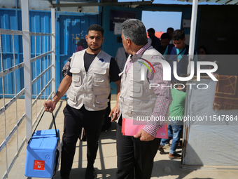 Health workers carry containers filled with polio vaccines during a vaccination campaign at the UK-MED field hospital in Khan Younis in the...