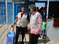 Health workers carry containers filled with polio vaccines during a vaccination campaign at the UK-MED field hospital in Khan Younis in the...