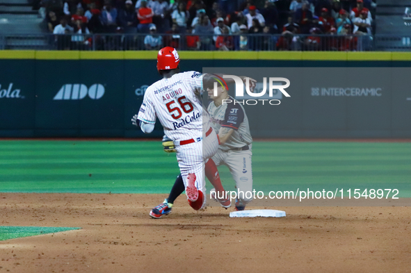 Aristides Aquino #56 of Diablos Rojos slides to avoid the tag by second baseman Ramiro Pena #19 of Sultanes de Monterrey during the match 1...