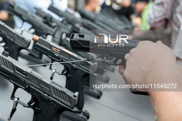 Visitors look at guns from UM as they attend the 32nd International Defence Industry Exhibition - MSPO i Targi Kielce in central Poland on S...