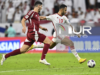 Karim Boudiaf (R) of Qatar battles for the ball with Khaled Aldhanhani (L) of the United Arab Emirates during the qualification 3rd round fo...