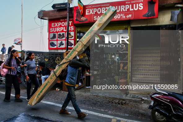 A laborer carries a heavy load of wood along the Mall Road in Mussoorie, Uttarakhand, India, on April 18, 2024. 