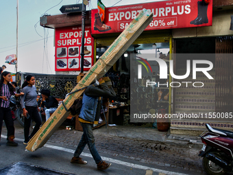 A laborer carries a heavy load of wood along the Mall Road in Mussoorie, Uttarakhand, India, on April 18, 2024. (