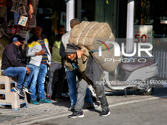 A laborer carries a heavy load along the Mall Road in Mussoorie, Uttarakhand, India, on April 18, 2024. (