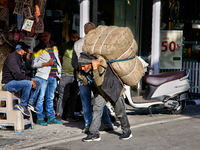 A laborer carries a heavy load along the Mall Road in Mussoorie, Uttarakhand, India, on April 18, 2024. (