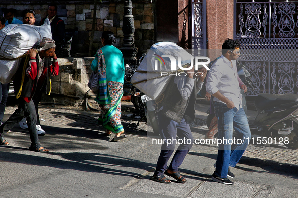 Laborers carry heavy loads along the Mall Road in Mussoorie, Uttarakhand, India, on April 18, 2024. 