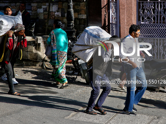 Laborers carry heavy loads along the Mall Road in Mussoorie, Uttarakhand, India, on April 18, 2024. (