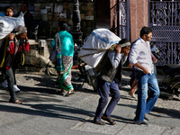 Laborers carry heavy loads along the Mall Road in Mussoorie, Uttarakhand, India, on April 18, 2024. (