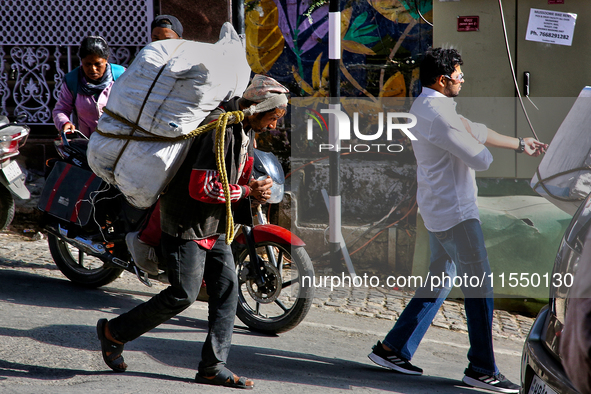 A laborer carries a heavy load along the Mall Road in Mussoorie, Uttarakhand, India, on April 18, 2024. 