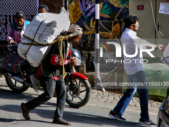 A laborer carries a heavy load along the Mall Road in Mussoorie, Uttarakhand, India, on April 18, 2024. (