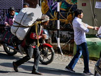 A laborer carries a heavy load along the Mall Road in Mussoorie, Uttarakhand, India, on April 18, 2024. (