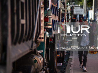 People commute by walking alongside roads filled with parked trucks as truckers demonstrate against the increase in diesel prices in Bogota,...