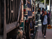 People commute by walking alongside roads filled with parked trucks as truckers demonstrate against the increase in diesel prices in Bogota,...