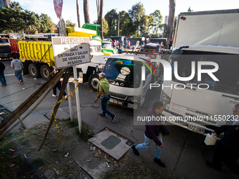 People commute by walking alongside roads filled with parked trucks as truckers demonstrate against the increase in diesel prices in Bogota,...