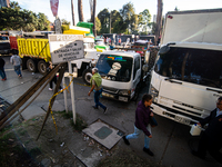 People commute by walking alongside roads filled with parked trucks as truckers demonstrate against the increase in diesel prices in Bogota,...