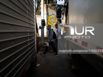 People commute by walking alongside roads filled with parked trucks as truckers demonstrate against the increase in diesel prices in Bogota,...