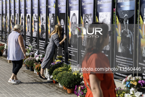 A woman kisses a portrait of a relative who dies in the war with Russia on the Alley of Glory of Heroes of Ukraine in Kremenets, Ternopil Ob...