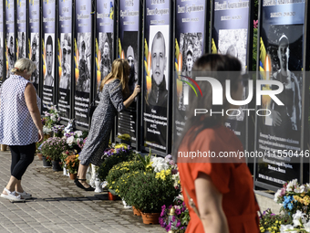 A woman kisses a portrait of a relative who dies in the war with Russia on the Alley of Glory of Heroes of Ukraine in Kremenets, Ternopil Ob...