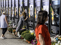 A woman kisses a portrait of a relative who dies in the war with Russia on the Alley of Glory of Heroes of Ukraine in Kremenets, Ternopil Ob...