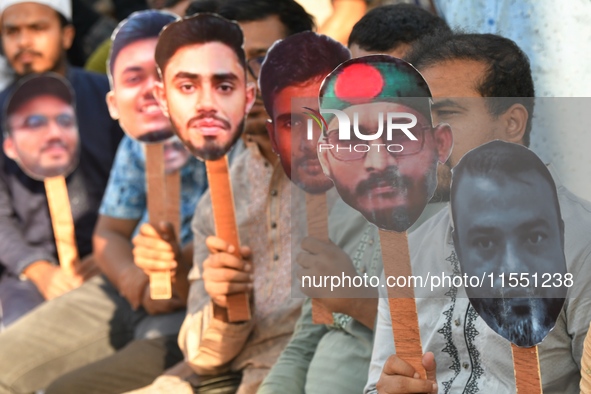 People hold placards with the faces of martyrs at the 'Shohidra Fire Ashche' event, held in memory of those killed in the anti-discriminatio...