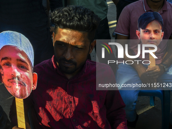 People hold placards with the faces of martyrs at the 'Shohidra Fire Ashche' event, held in memory of those killed in the anti-discriminatio...