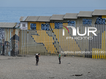 Two tourists take a selfie while posing near a new interactive mural of deported veterans at the Playas de Tijuana beach border wall, ''The...