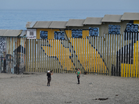 Two tourists take a selfie while posing near a new interactive mural of deported veterans at the Playas de Tijuana beach border wall, ''The...