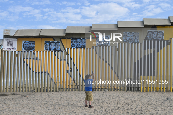 A man takes pictures with his cell phone of a new interactive mural of deported veterans at the Playas de Tijuana beach border wall, ''The D...