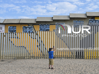 A man takes pictures with his cell phone of a new interactive mural of deported veterans at the Playas de Tijuana beach border wall, ''The D...