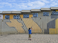 A man takes pictures with his cell phone of a new interactive mural of deported veterans at the Playas de Tijuana beach border wall, ''The D...