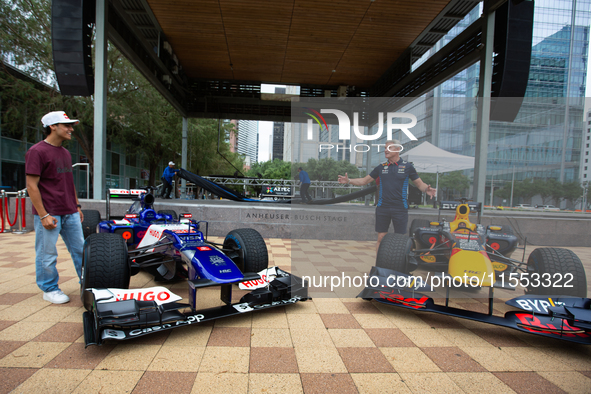 Former Formula 1 driver David Coulthard and Red Bull Junior Driver Arvid Lindblad stand next to two championship-winning F1 cars, an RB7 and...