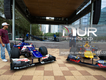 Former Formula 1 driver David Coulthard and Red Bull Junior Driver Arvid Lindblad stand next to two championship-winning F1 cars, an RB7 and...