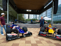 Former Formula 1 driver David Coulthard and Red Bull Junior Driver Arvid Lindblad stand next to two championship-winning F1 cars, an RB7 and...