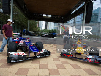 Former Formula 1 driver David Coulthard and Red Bull Junior Driver Arvid Lindblad stand next to two championship-winning F1 cars, an RB7 and...