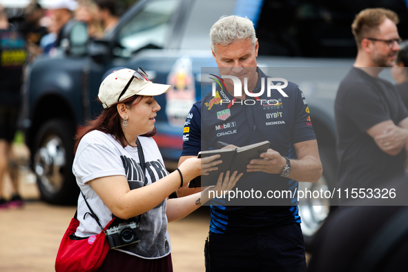 Former Formula 1 driver David Coulthard signs something for a fan at a private preview event for Red Bull's Houston Showrun in Houston, Texa...