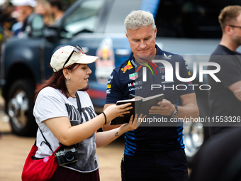 Former Formula 1 driver David Coulthard signs something for a fan at a private preview event for Red Bull's Houston Showrun in Houston, Texa...