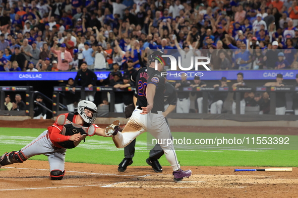 New York Mets Pete Alonso #20 beats the throw to score as Reds catcher Tyler Stephenson #37 tries to make the tag during the sixth inning of...