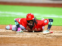 Elly De La Cruz #44 of the Cincinnati Reds hits the ground after avoiding a pitch during the ninth inning of the baseball game against the N...