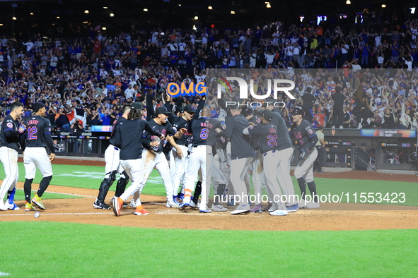 New York Mets' Mark Vientos #27 is mobbed by teammates at home plate after a 10th inning game-winning home run to give the Mets a 6-4 victor...