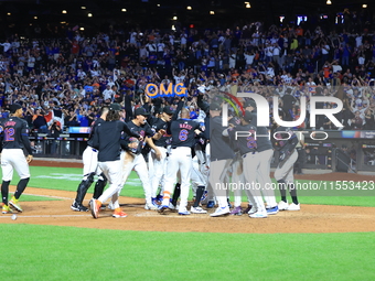 New York Mets' Mark Vientos #27 is mobbed by teammates at home plate after a 10th inning game-winning home run to give the Mets a 6-4 victor...