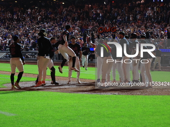 New York Mets' Mark Vientos #27 is mobbed by teammates at home plate after a 10th inning game-winning home run to give the Mets a 6-4 victor...