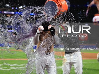 New York Mets' Mark Vientos #27 receives a Gatorade and water bath from teammates after his 10th inning game-winning home run lifts the Mets...