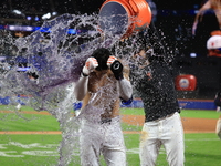 New York Mets' Mark Vientos #27 receives a Gatorade and water bath from teammates after his 10th inning game-winning home run lifts the Mets...