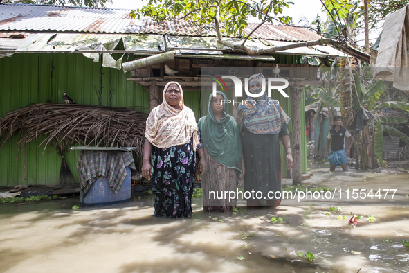 Three women stand in front of their flood-damaged houses in a village in Chaumuhni Municipality of Noakhali District, Chittagong Division, B...