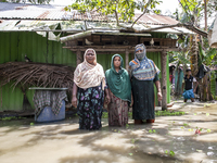 Three women stand in front of their flood-damaged houses in a village in Chaumuhni Municipality of Noakhali District, Chittagong Division, B...