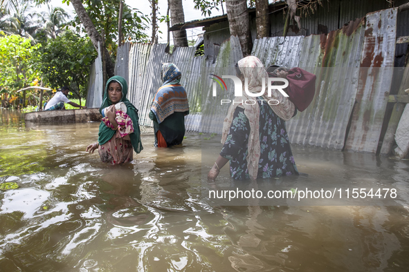 Women walk through waist-deep flood water in a village of Chaumuhni Municipality in Noakhali District of Chittagong Division in Noakhali, Ch...