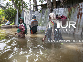 Women walk through waist-deep flood water in a village of Chaumuhni Municipality in Noakhali District of Chittagong Division in Noakhali, Ch...