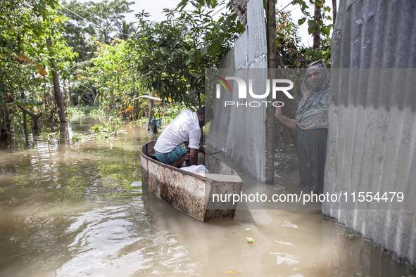 A man prepares his boat to go to the market in knee-deep flooded water in a village in Chaumuhni Municipality of Noakhali District, Chittago...