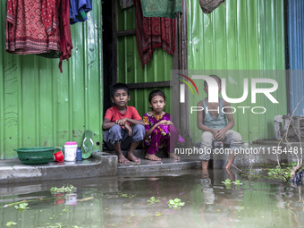 Three children sit in front of their flooded house in a village of Chaumuhni Municipality in Noakhali District in Chittagong, Bangladesh, on...