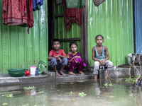 Three children sit in front of their flooded house in a village of Chaumuhni Municipality in Noakhali District in Chittagong, Bangladesh, on...